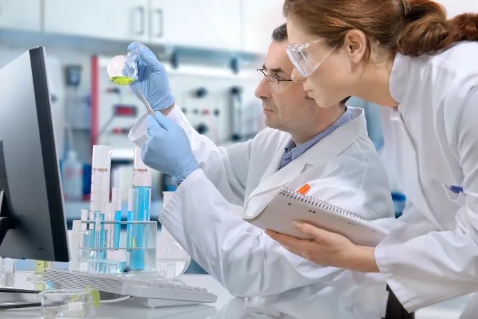 Dos científicos examinando un matraz en el laboratorio